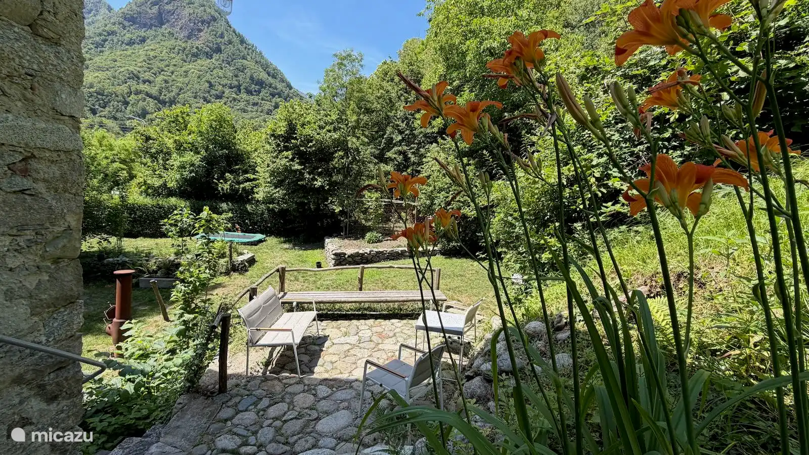 Geniet van het prachtige panoramische uitzicht op de groene bergen van Valsesia vanuit de tuin van Appartement Stella in Piemonte. Ontspan op het sfeervolle terras, omringd door bloemen en natuur.