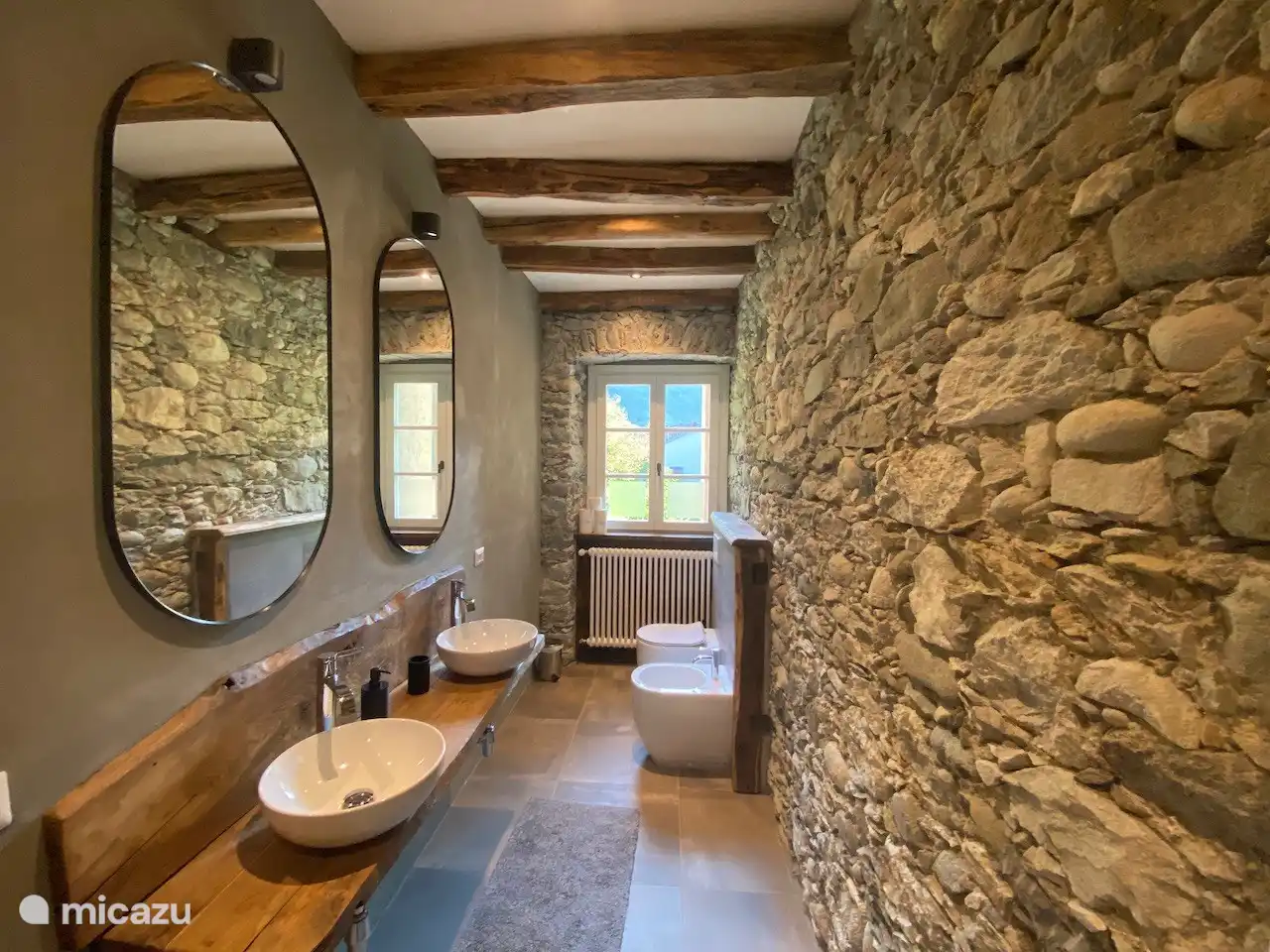 Badkamer met regendouche, dubbele wastafel, wc en bidet. Handdoeken zijn aanwezig.