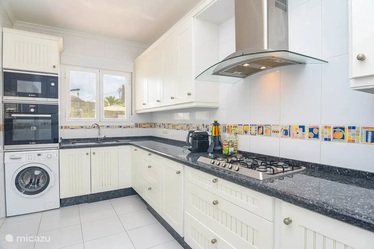 Modern kitchen with microwave, oven, gas hob, dishwasher, washing machine, fridge and Nespresso machine.