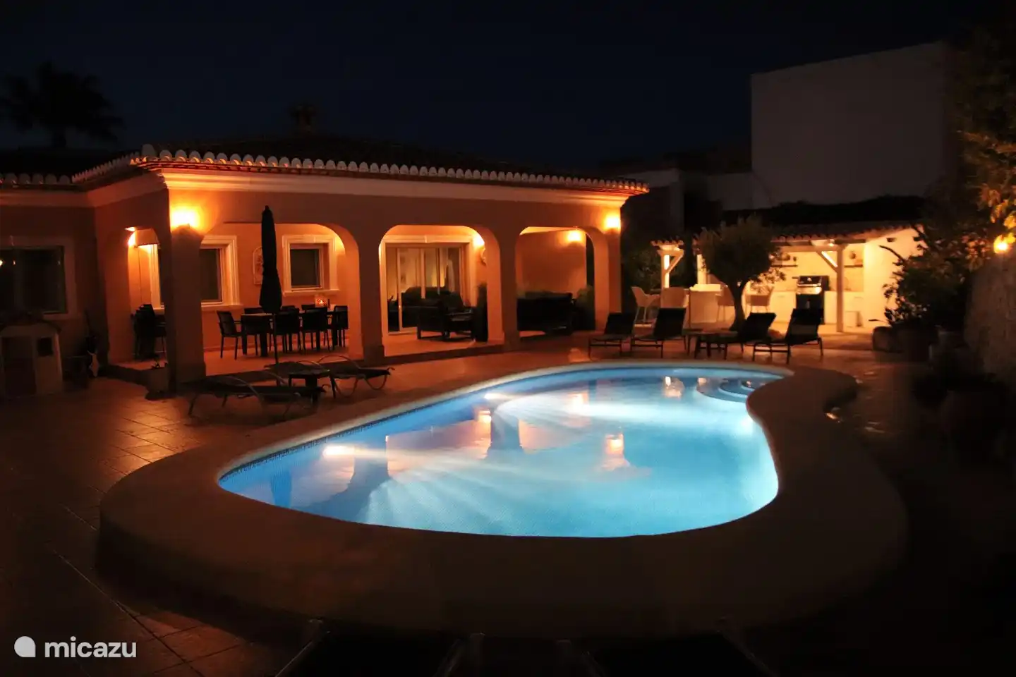 Stimmungsvoller Blick auf Schwimmbad, Garten und Haus bei Nacht