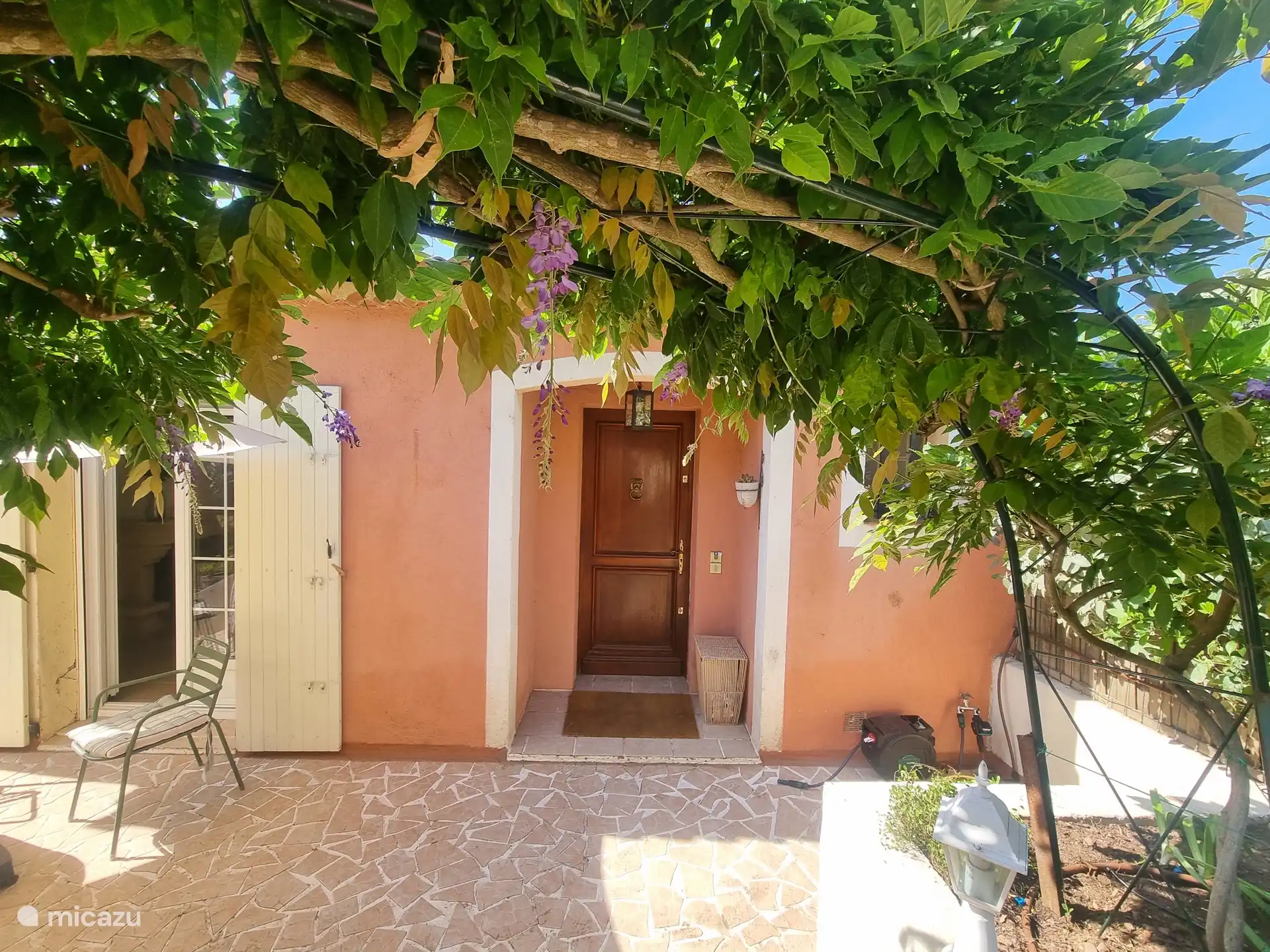 Aan de zuidzijde de voordeur en openslaande deuren vanuit de woonkamer naar het terras.