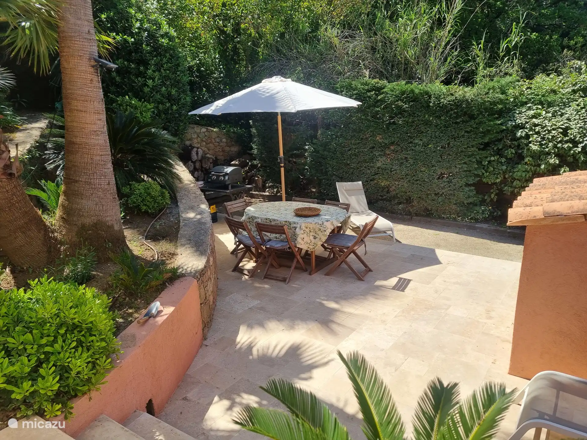 terras naast de petanquebaan met eettafel en ligbedden. 