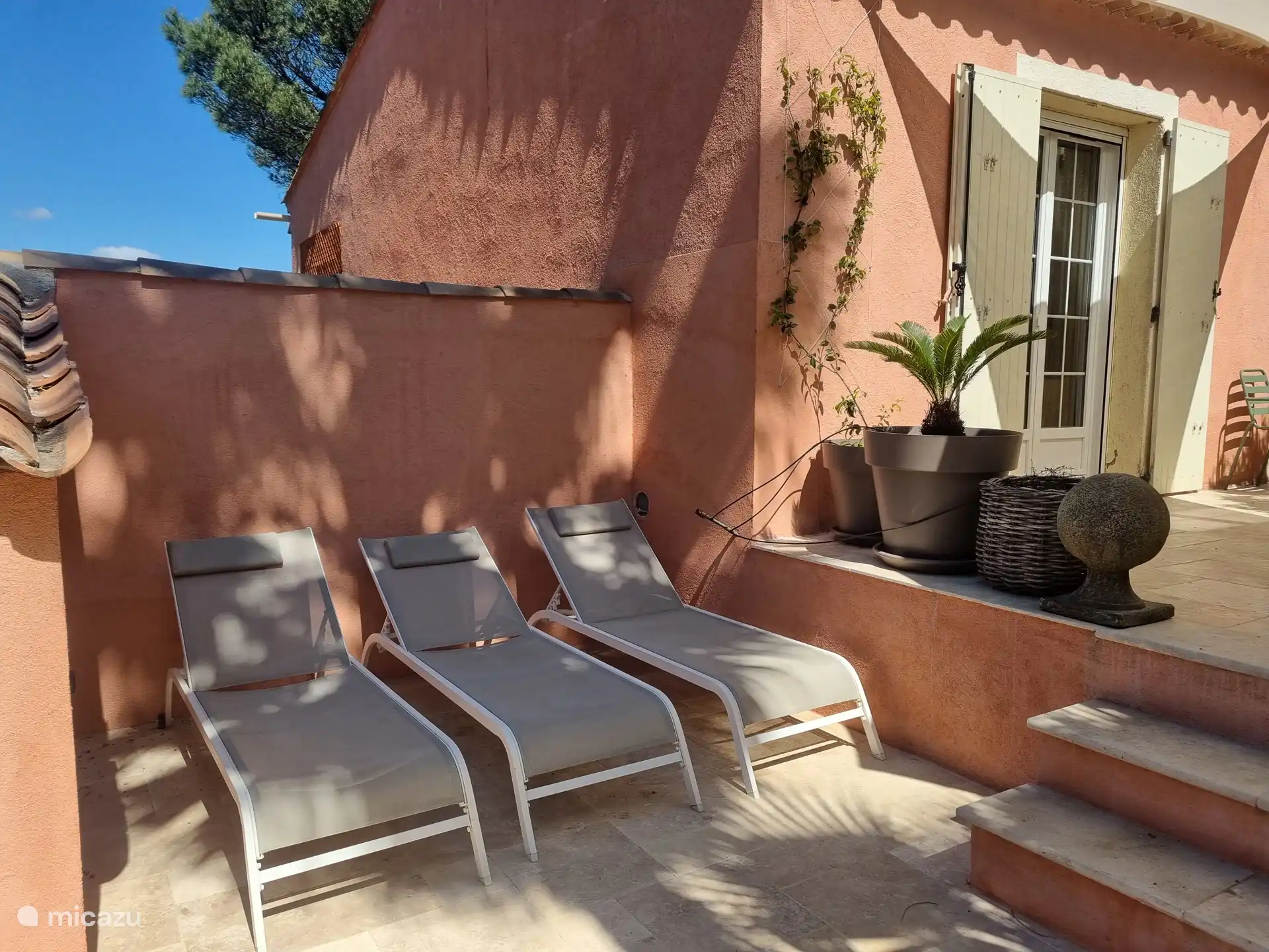 beschut terras met zon/schaduw van de palmboom. Er zijn in totaal 6 ligbedden bij het huis. 