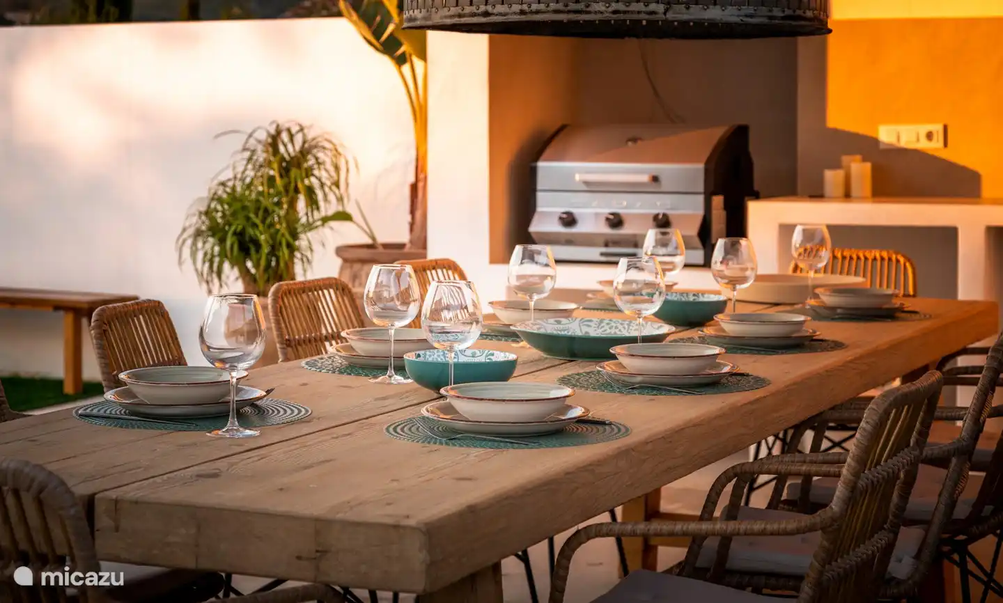 La cuisine extérieure dispose d'un barbecue à gaz, d'un réfrigérateur et d'un évier, d'une longue table à manger confortable et d'une belle vue sur la piscine.
