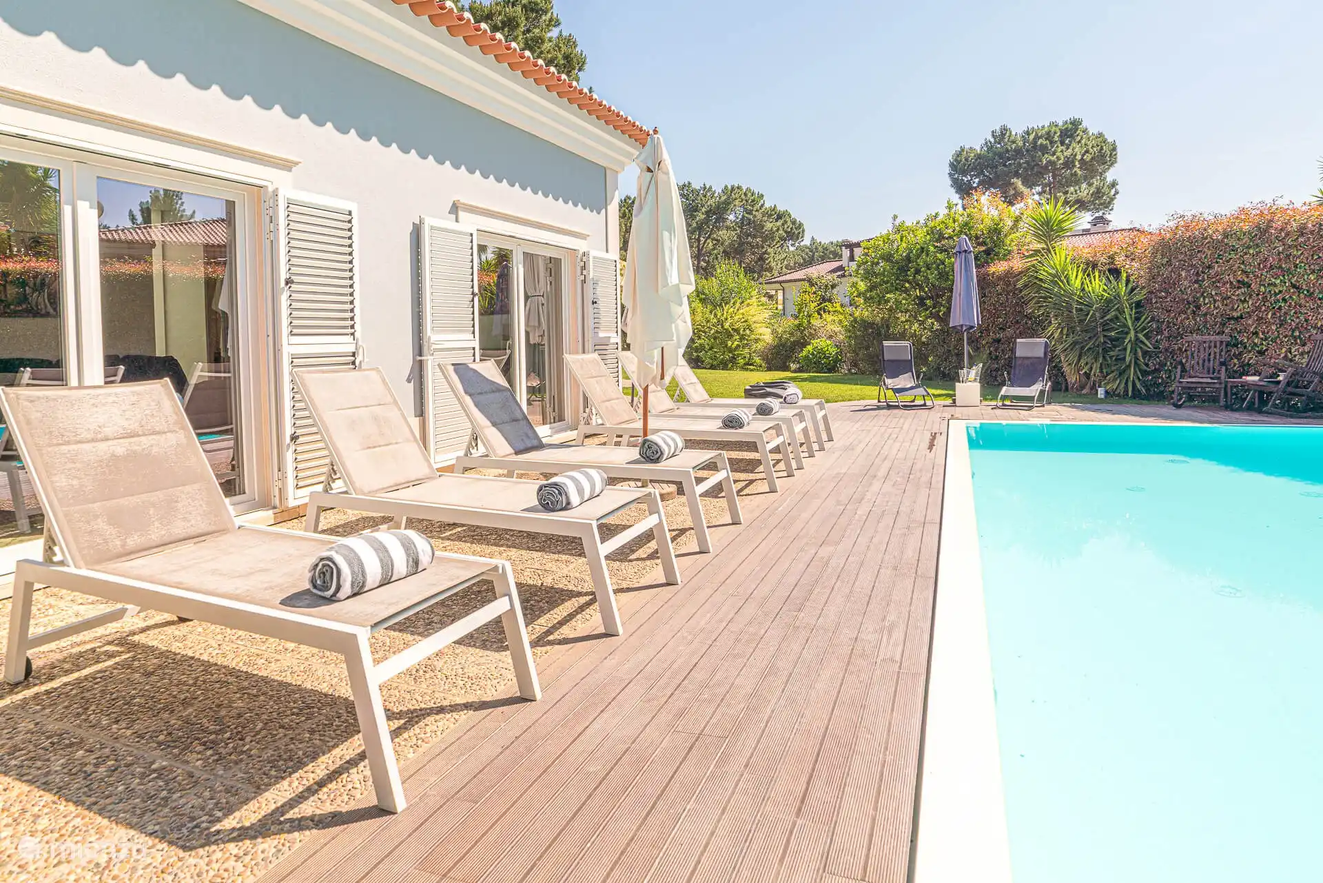 Terrasse mit Sonnenliegen entlang des Pools