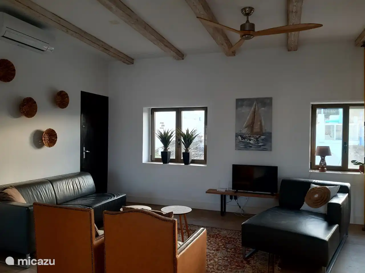 the spacious living room with TV, sitting area with 2 leather sofas