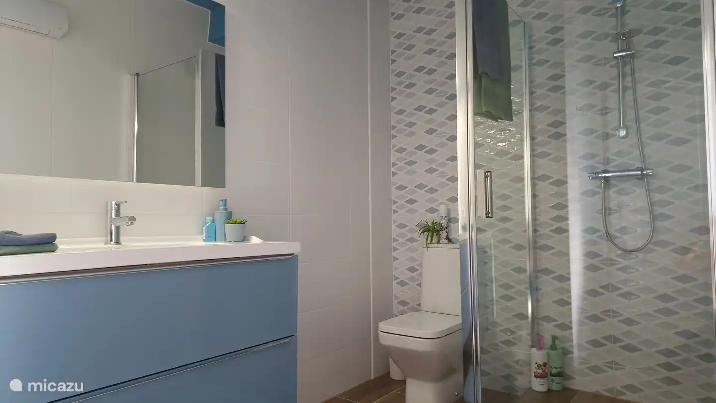 Ba&#241;o dormitorio azul equipado con una bonita ducha que incluye champ&#250;, acondicionador y gel de ducha. Un lavabo con jab&#243;n de manos, des. gel, toallas y secador de pelo. Inodoro, ventilador y calentador. 
