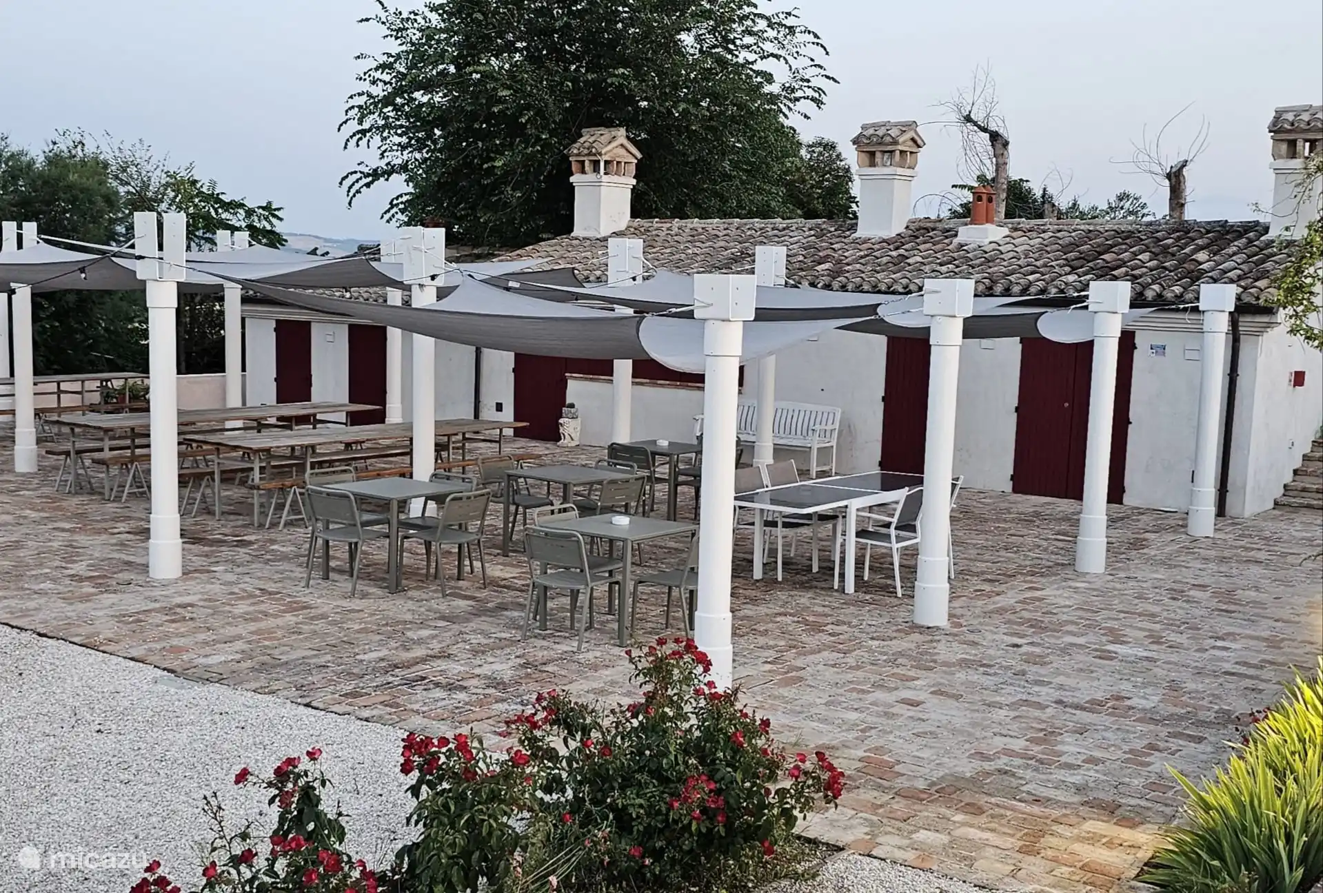 The pergola with ample shade, long tables, toilets, dressing room and communal laundry room. Our outdoor kitchen is the beating heart during the theme evenings.