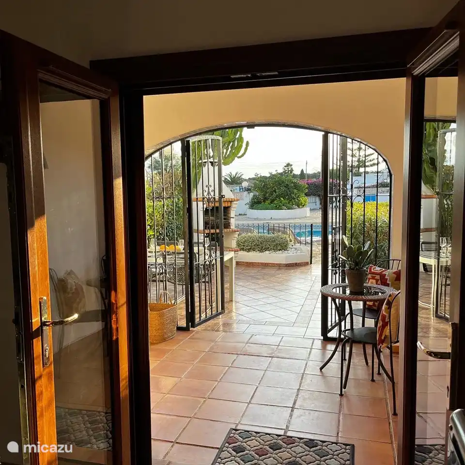 Vista desde el salón, al patio, jardín y piscina.