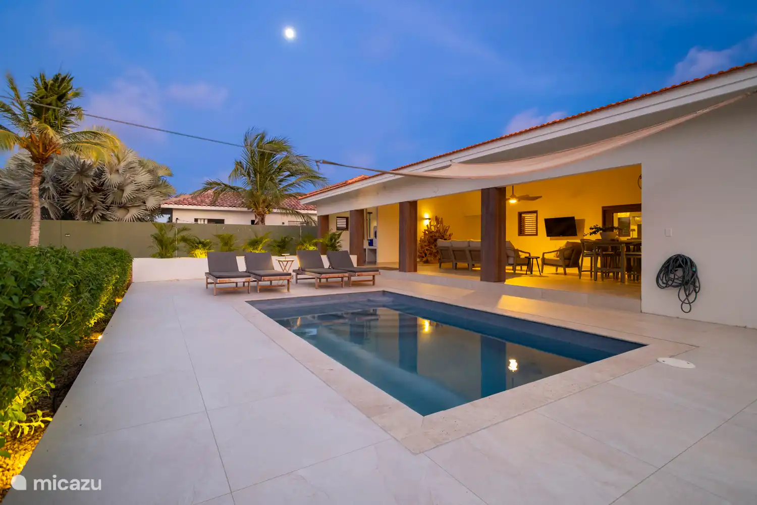 Kas Sinku - Sunrentals Bonaire pool deck with sunbeds and porch at dusk