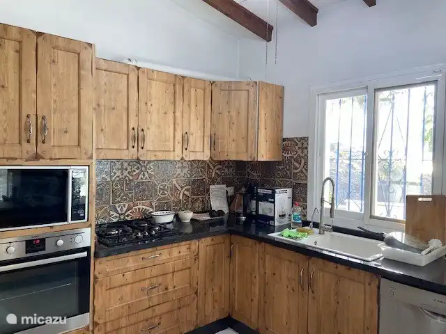 Praktisch ausgestattete Küche, die mit dem Wohnzimmer mit Sitz- und Essbereich verbunden ist.