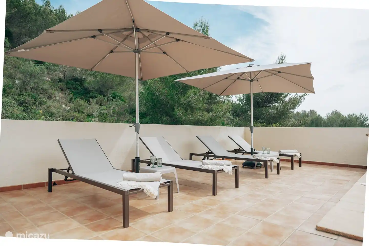 Sonnenliegen und Sonnenschirme auf der Terrasse neben dem Pool