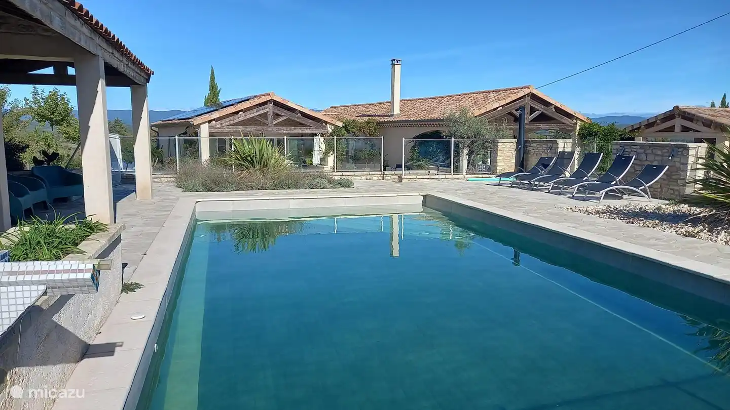 Piscine avec pool house et douche extérieure et transats.