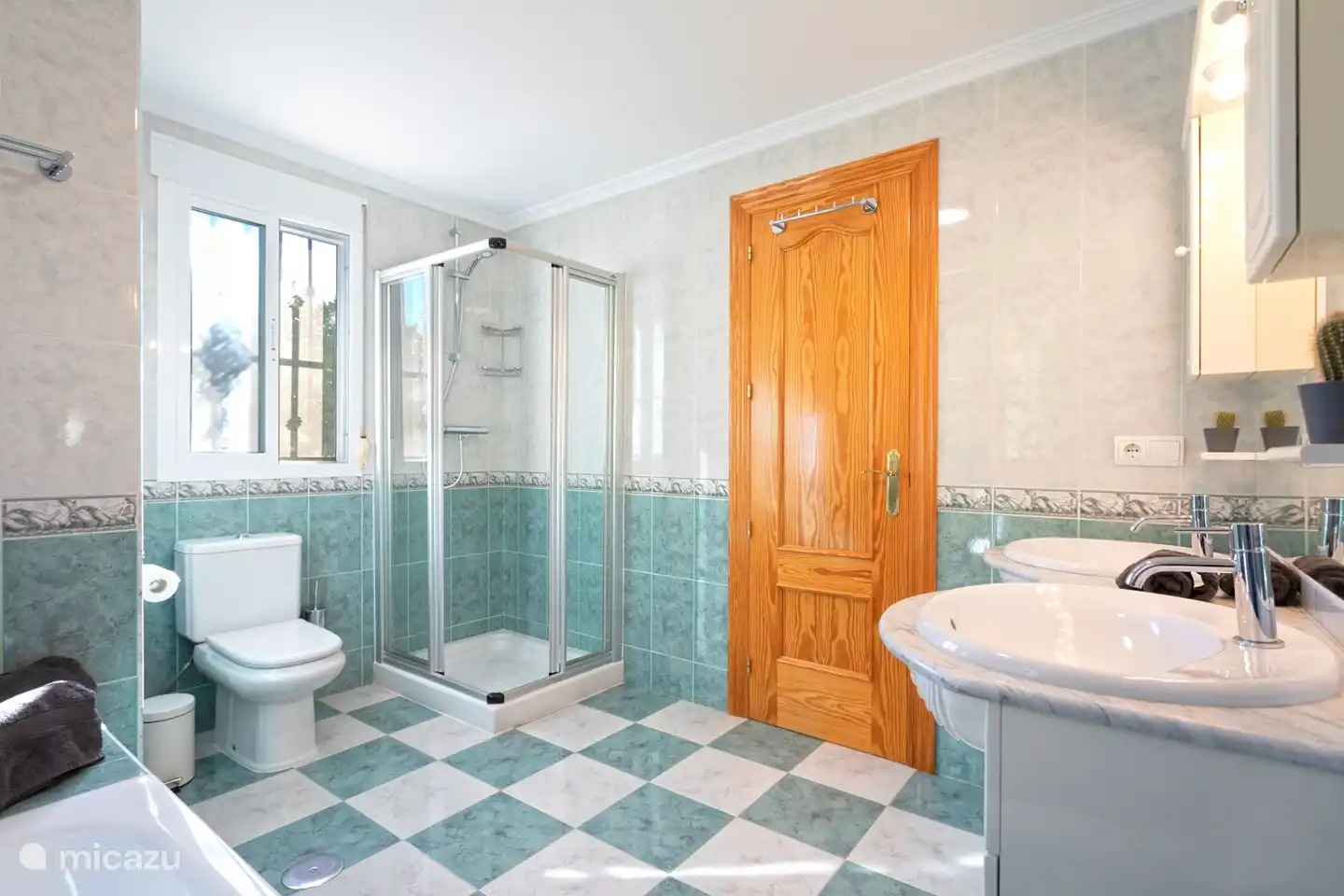 Badezimmer mit Dusche, Badewanne, Doppelwaschbecken und Toilette.