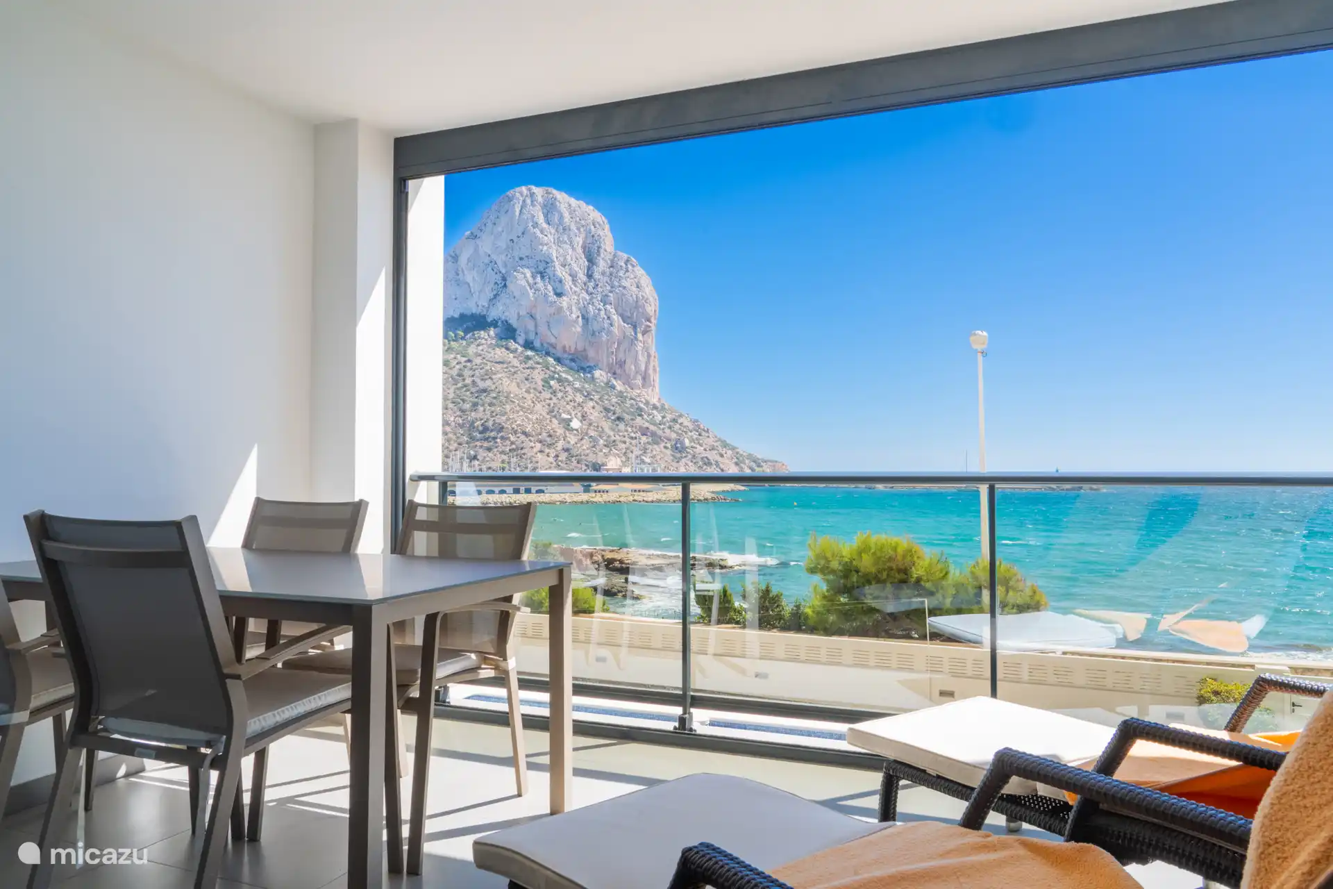 Overdekt balkon met eettafel en ligbedjes