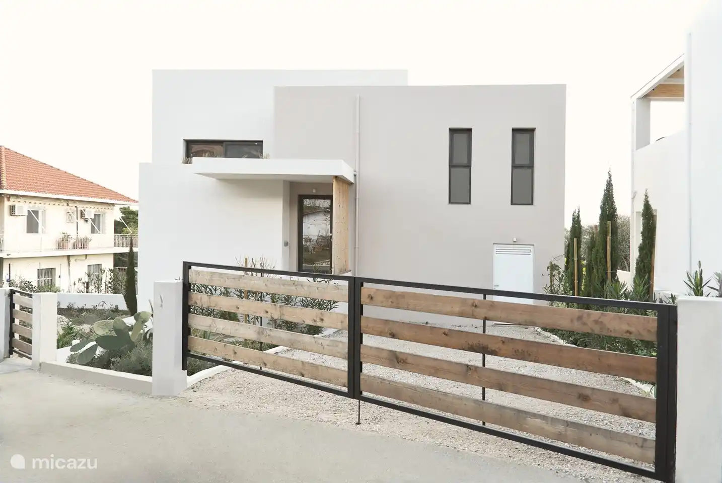 Votre première vue de la maison, l’avant avec entrée et place de parking spacieuse, vous surprendra par la végétation désormais mature