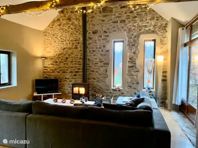 Location de Vacances France, Puy-de-Dôme, Teilhet, maison de vacances - Malguette Salon au premier étage dans l’ancien grenier à grains. Le salon dispose d’un poêle à bois. Ici, vous pourrez passer d’agréables soirées en dégustant un délicieux vin local tout en profitant du feu de bois crépitant en arrière-plan.
