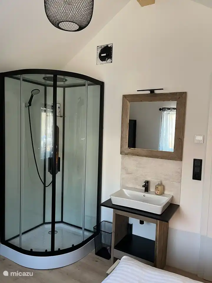 Slaapkamer boven achterzijde met douchecabine en wastafel.