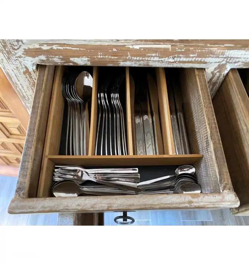 The cutlery in the drawer of the sideboard.
