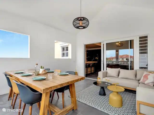 Villas sur l'Eau Appartement 3 Chambres | Bonaire, Bonaire, Kralendijk - appartement Balcon couvert avec canapé salon et table à manger avec 6 chaises. Du balcon couvert, vous avez une belle vue sur l'eau.