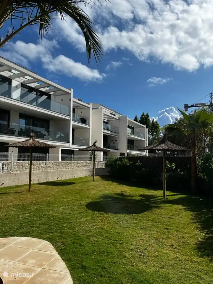 Lovely garden by the communal swimming pool with parasols