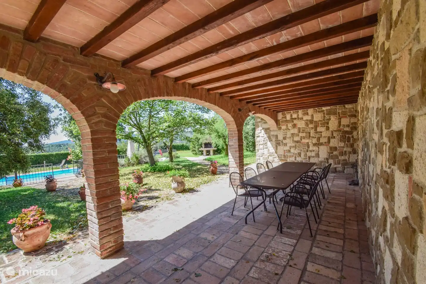 Aan de voorzijde van de villa is een groot overdekt met tafel en stoelen