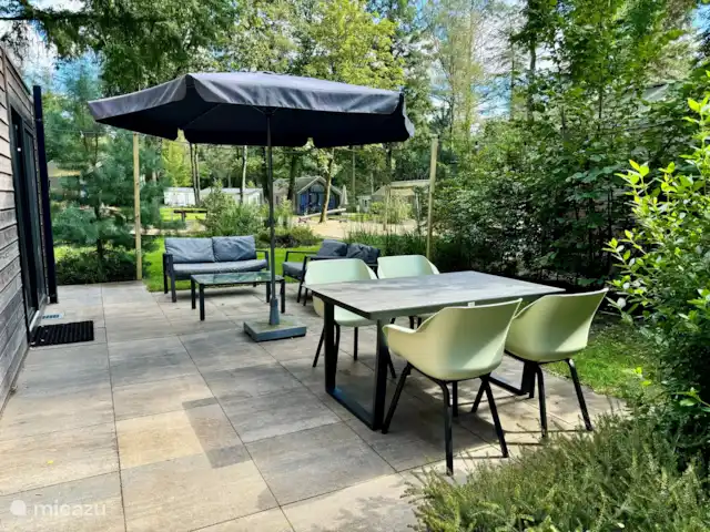 chalet en Países Bajos, Güeldres, Arnhem – Casa de vacaciones Maridu Wellness La terraza con un sofá lounge y una mesa de comedor con 4 plazas. Sentado cómodamente o cuando tenga visitas.