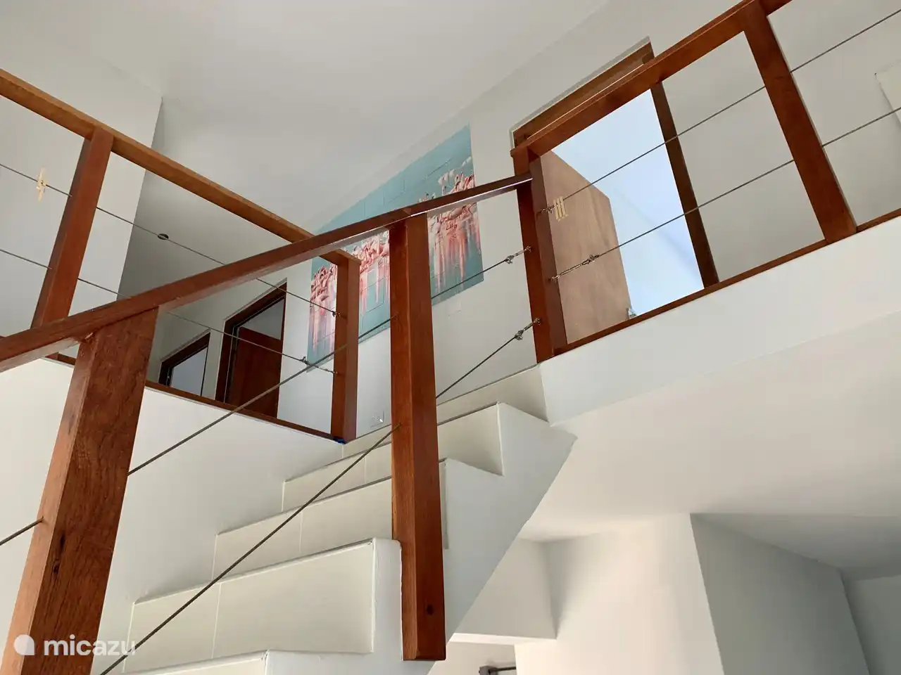 Vanuit de keuken een open trap naar de bovenverdieping, met als blikvanger de flamingo's.