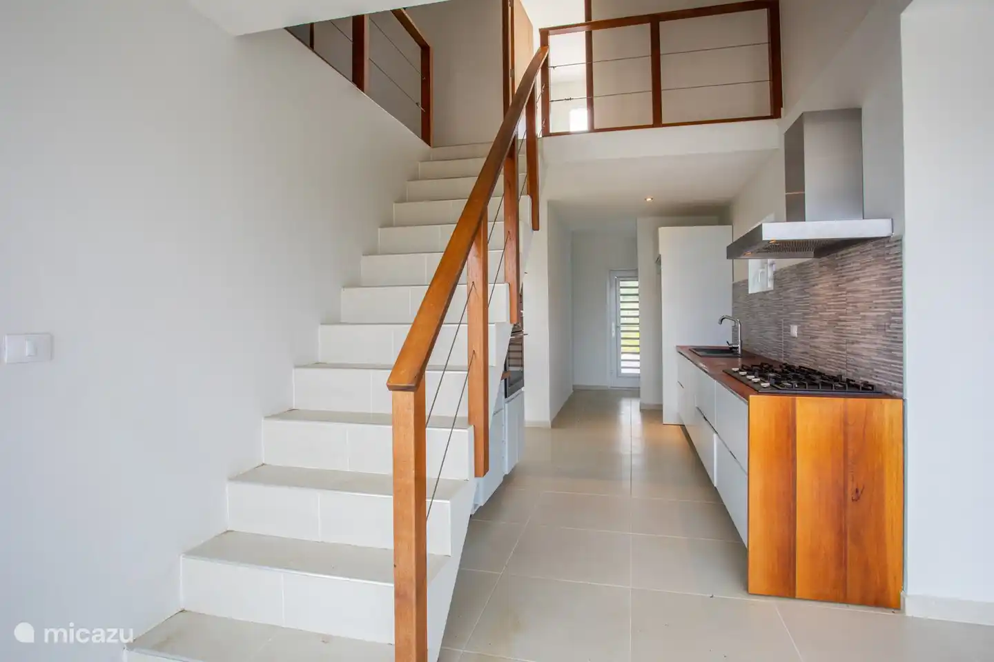 Vanuit de woonkamer loop je zo de open keuken in en door de hoogte is de beleving groot en ruim. Vanuit de keuken loop je naar boven.