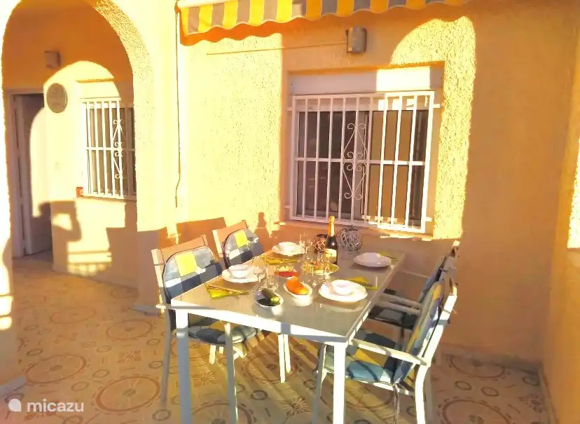 terrasje aan de achterkant in avondzon, met zicht op tuin en zwembad