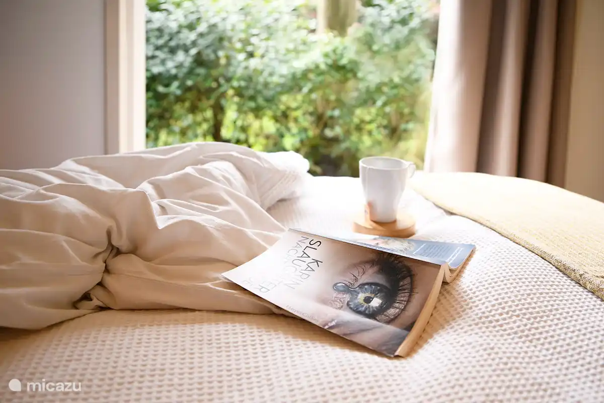 Lesen Sie ein Buch im Bett, während die Vögel im Garten zwitschern 