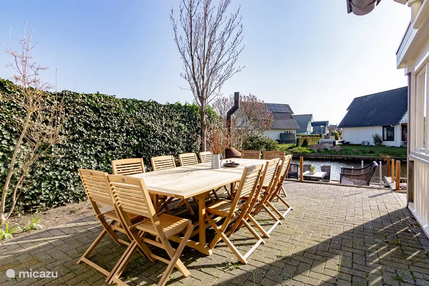 Dans le jardin, il y a une très grande table extérieure où 12 personnes peuvent manger. C'est sur la terrasse sur l'eau à côté de la véranda.