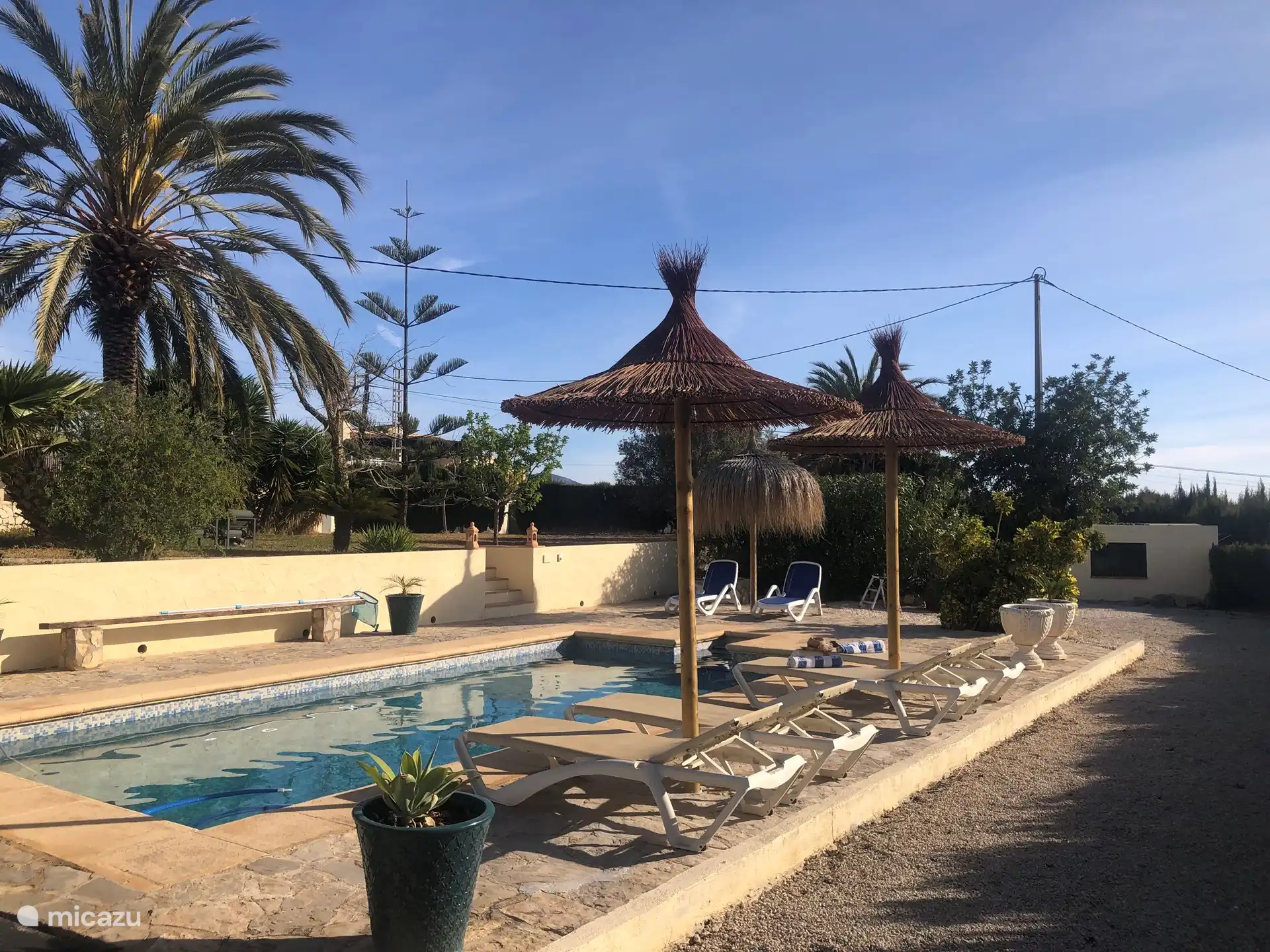 Zwembad met vaste parasols die fijne schaduw geven onder de ligbedden