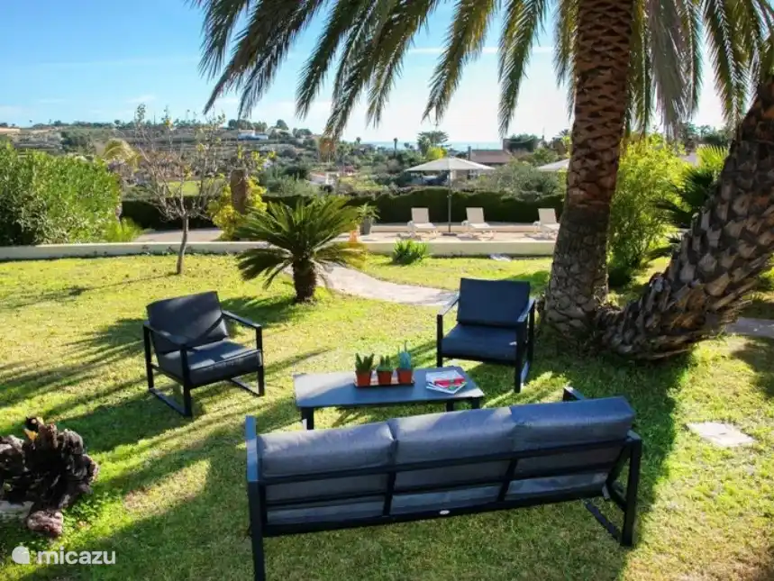 Grote besloten terrassen tuin met veel planten en bomen.