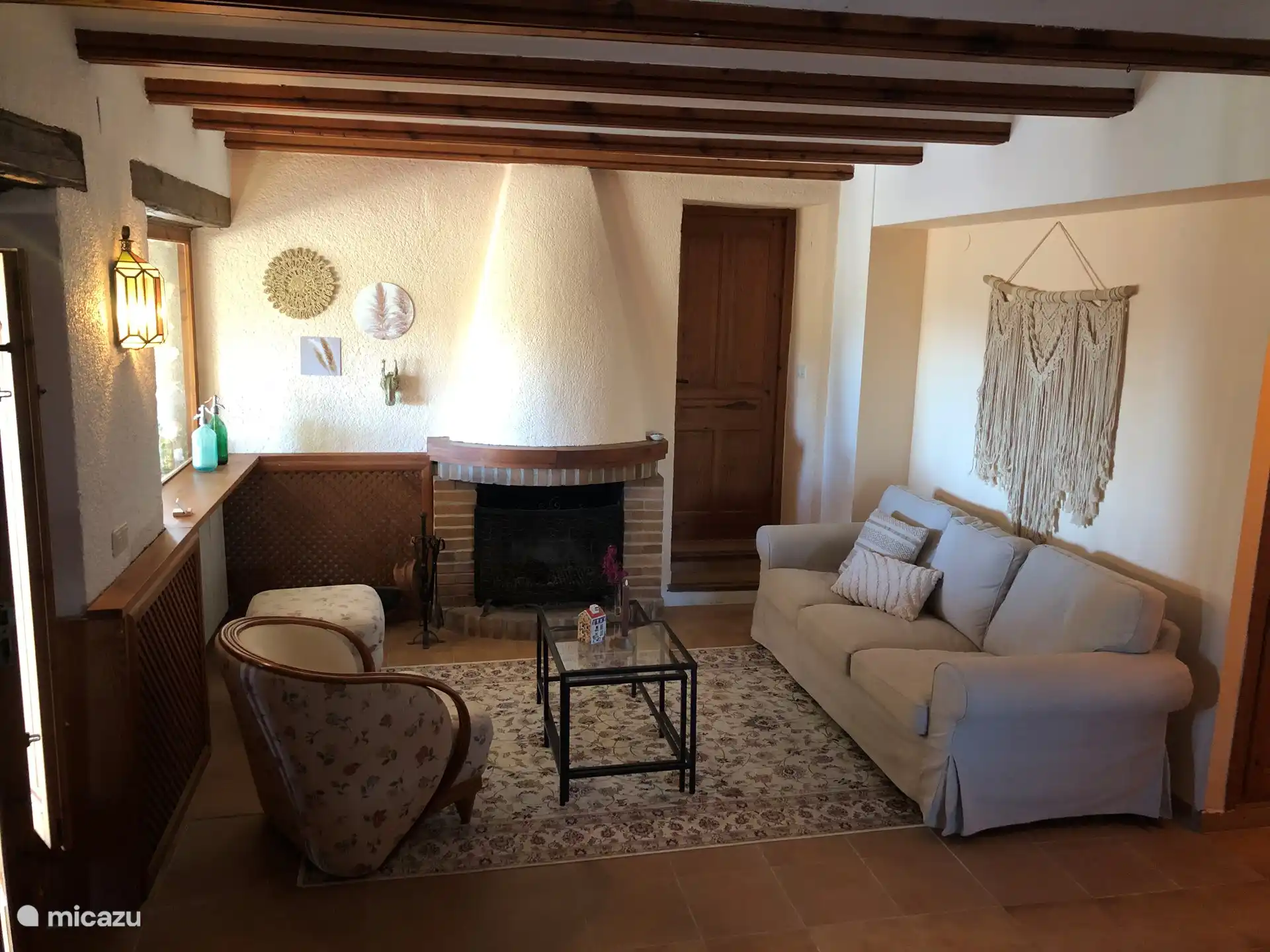 De living, woonkamer II met open haard, bank, eettafel en stoelen. Keuken, badkamer en 2 slaapkamers komen hieropuit.