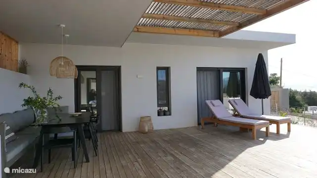 Zona exterior con la mesa del comedor y las habitaciones detrás