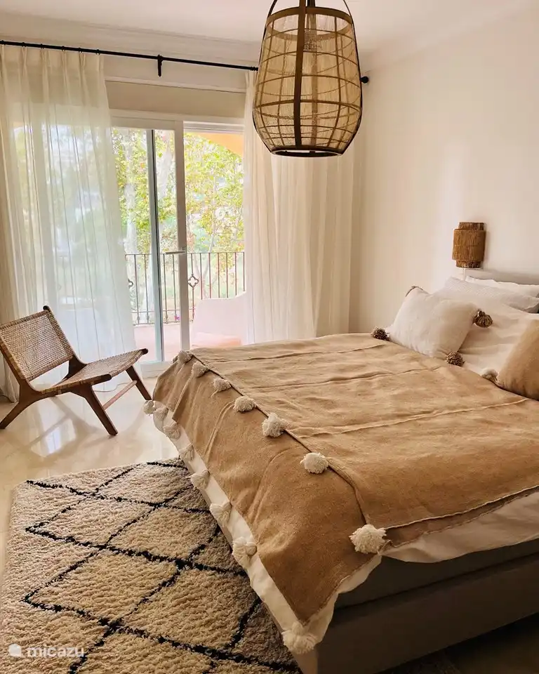 Weißes Schlafzimmer im Obergeschoss mit Doppelbett und großem Balkon. Privates Badezimmer mit großer ebenerdiger Dusche.