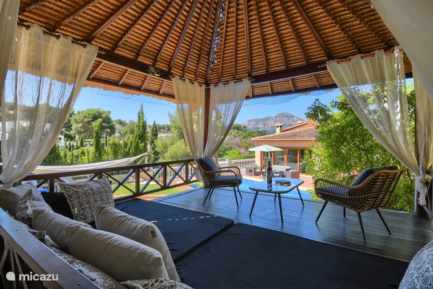 Gazebo balinais en bois dur tropical. L'endroit idéal pour se prélasser, lire, somnoler et boire un verre. Parfaitement frais et avec vue sur le Montgó. endroit préféré des enfants sur les grands coussins du salon