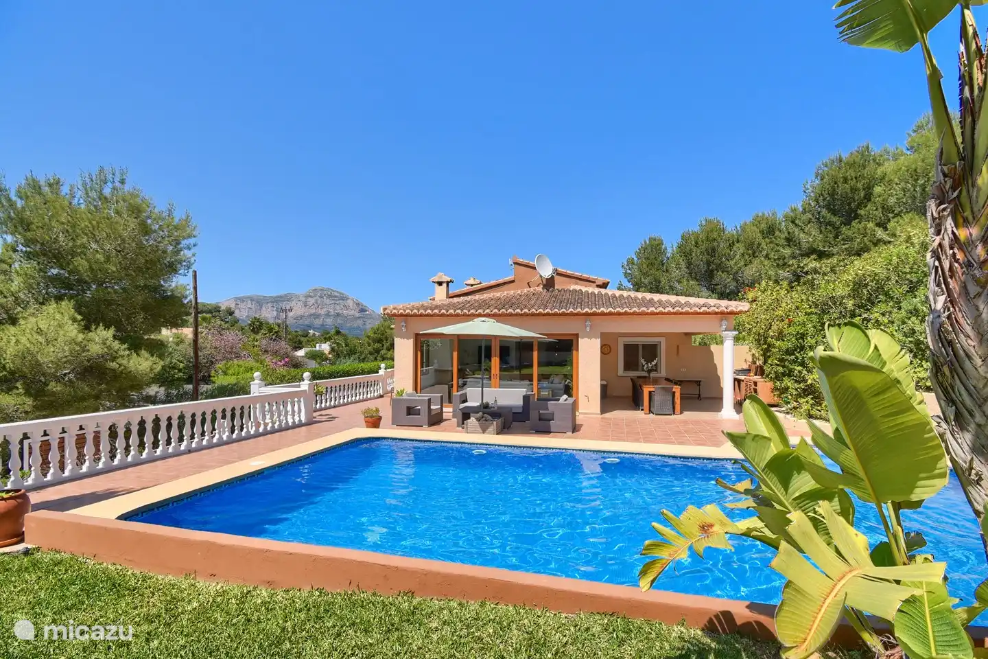 Vue sur la piscine depuis la maison balinaise dans le jardin.