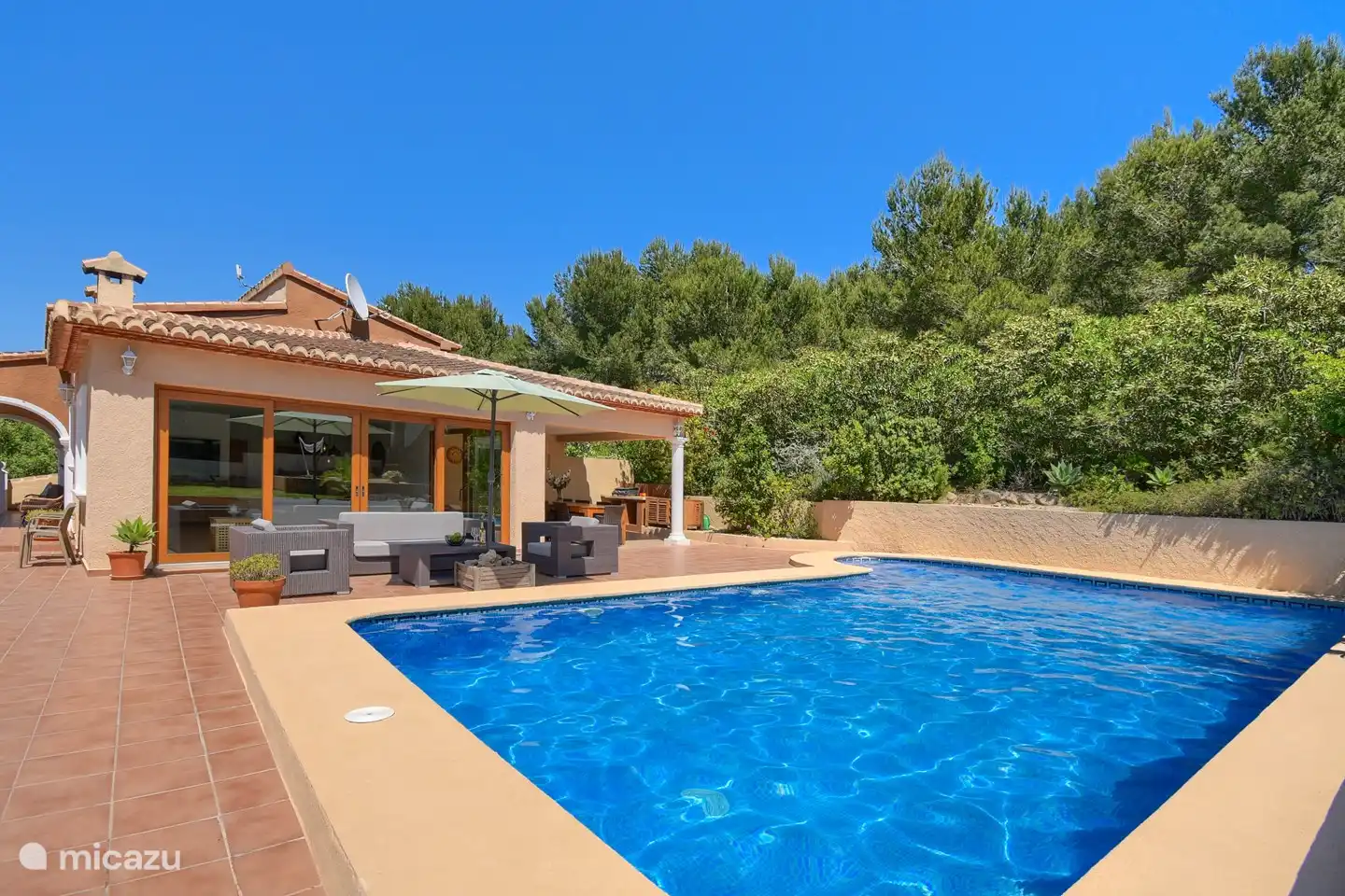 Piscine avec vue sur l'ensemble salon et cuisine extérieure dans la pinède.