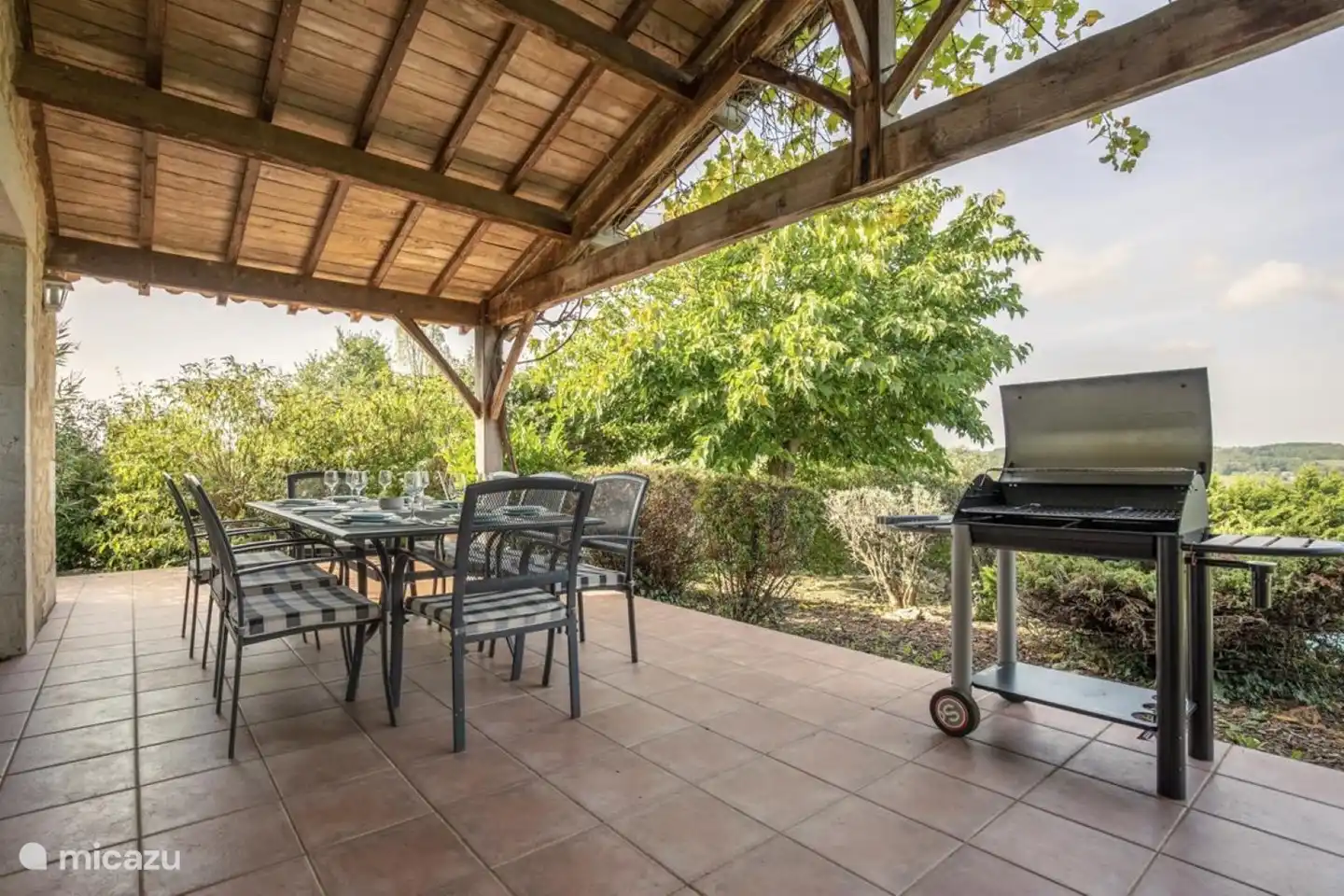 Großer Esstisch und Grill auf der überdachten Terrasse