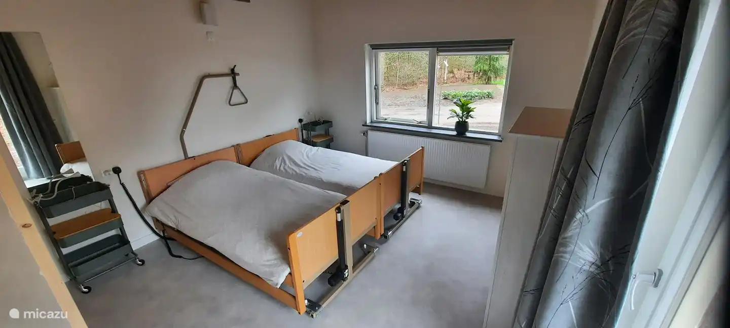 Dormitorio con camas altas y bajas eléctricas y baño en suite.