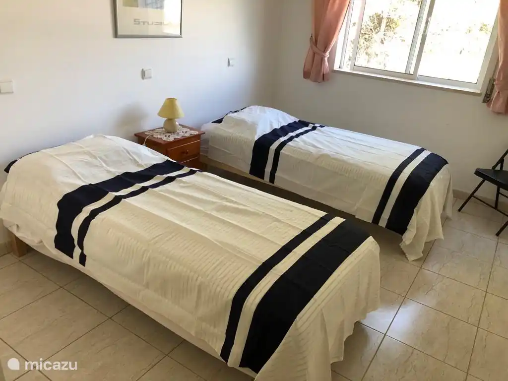 Chambre 2, également spacieuse et équipée de deux lits simples, table de chevet et placard pour un espace de rangement suffisant.