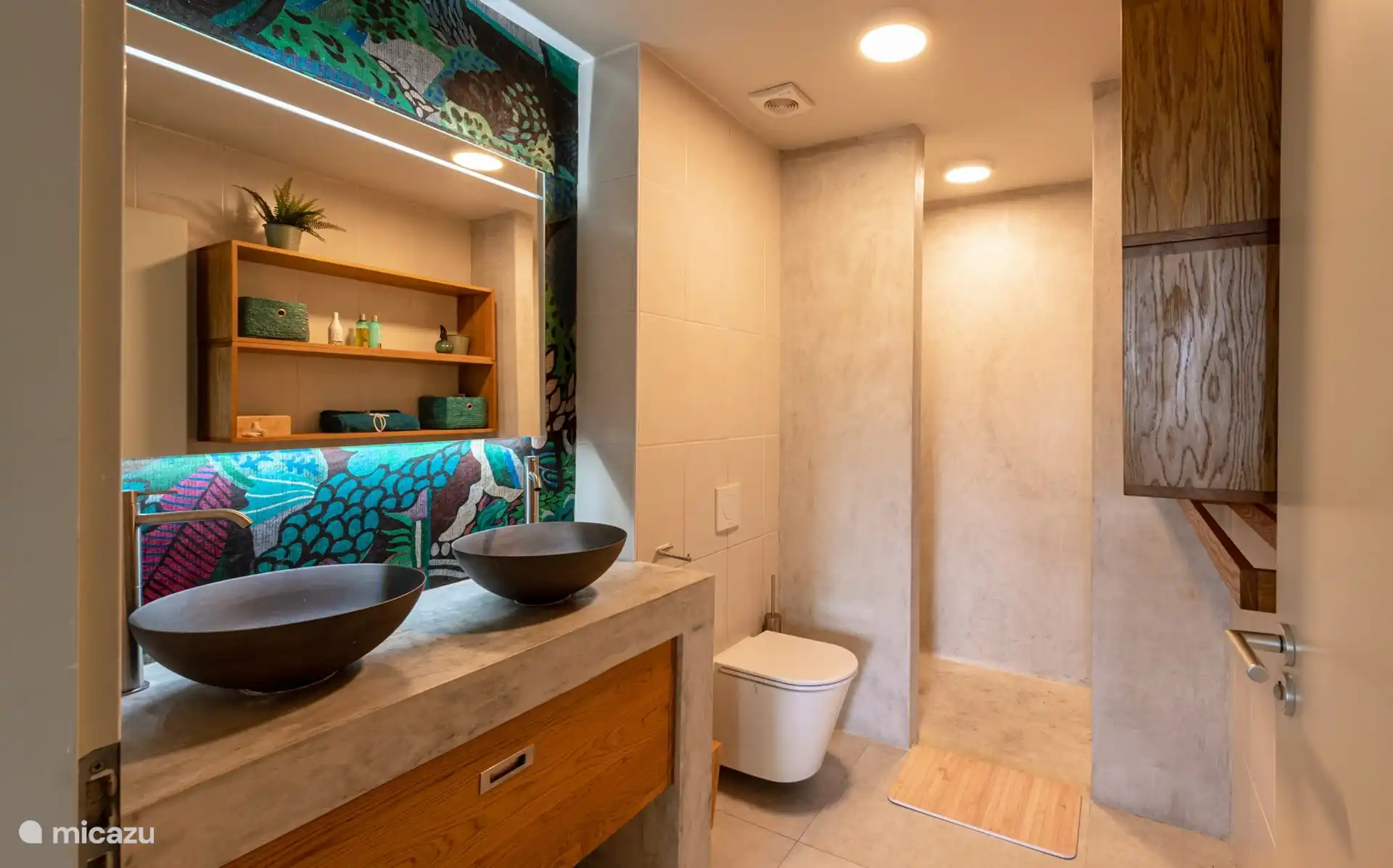 La salle de bain spacieuse avec double vasque, un grand espace de rangement (avec un sèche-cheveux dans l’un des tiroirs) et la douche.