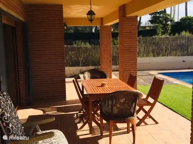 Casa José Ramón en España, Costa Dorada, Tarragona - casa vacacional Terraza techada, 2 mesas con sillas y vista a la piscina. Gran ventana corrediza al comedor y sala de estar.
