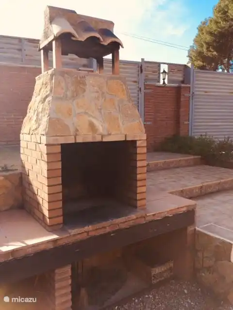 Zicht op BBQ, daarnaast is een buiten lavabo. Zicht op deur straatkant en poort straatkant.