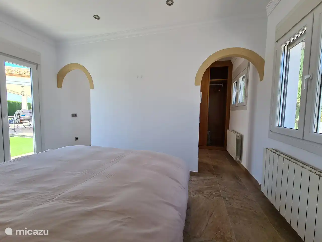 Grote slaapkamer #2 met kastenwand achter de muur. Directe toegang tot de tuin.