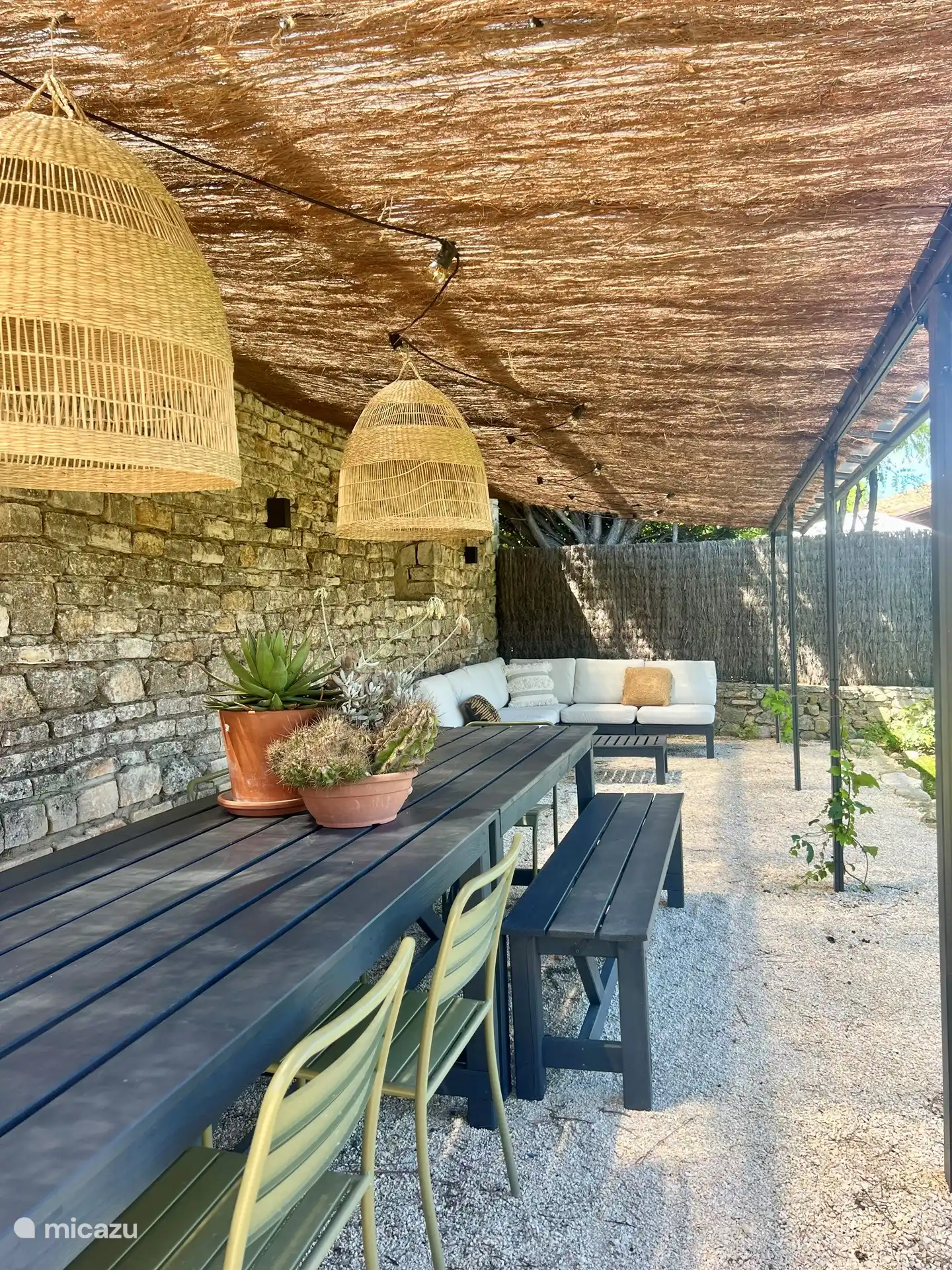 Toldo en el jardín con sofá lounge y amplia mesa de comedor
