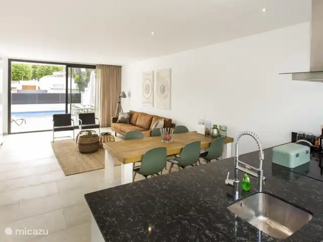 vakantiehuis huren in Spanje, Costa Brava, Empuriabrava – 6 persoons Villa Woonkamer vanuit de keuken bekeken met een prachtig uitzicht naar het zwembad en de tuin met terras. In de woonkamer is een airco aanwezig.