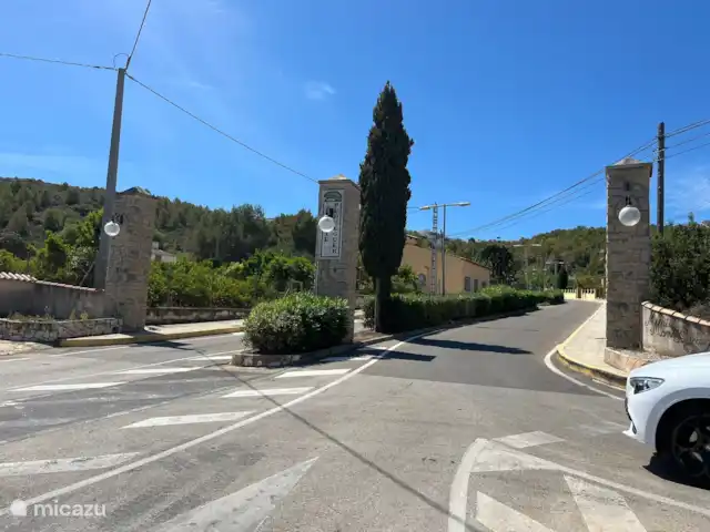 Casa Yavari en España, Costa Blanca, Pedreguer  - villa Acceso a la Urbanización Monte Pedreguer
Imponente puerta de entrada con pilares de piedra, dotada de iluminación ambiental y rodeada de exuberantes plantas. Una entrada elegante que refleja el encanto de la urbanización.